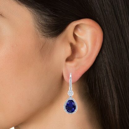 Close-up of white gold sapphire diamond dangle earring worn on a model's ear