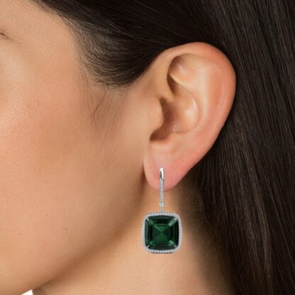 Close-up of green gemstone diamond halo earring worn on a model's ear