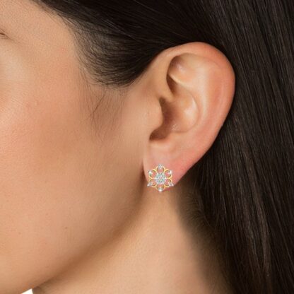 Close-up of yellow gold diamond snowflake stud earring worn on a model's ear