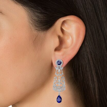 Close-up of white gold sapphire diamond chandelier earring worn on a model's ear
